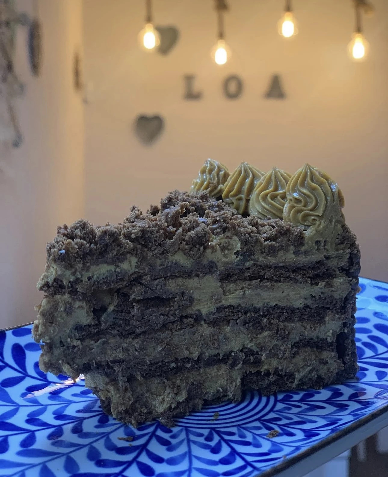 Porción de chocotorta con dulce de leche, con luces del local de fondo
