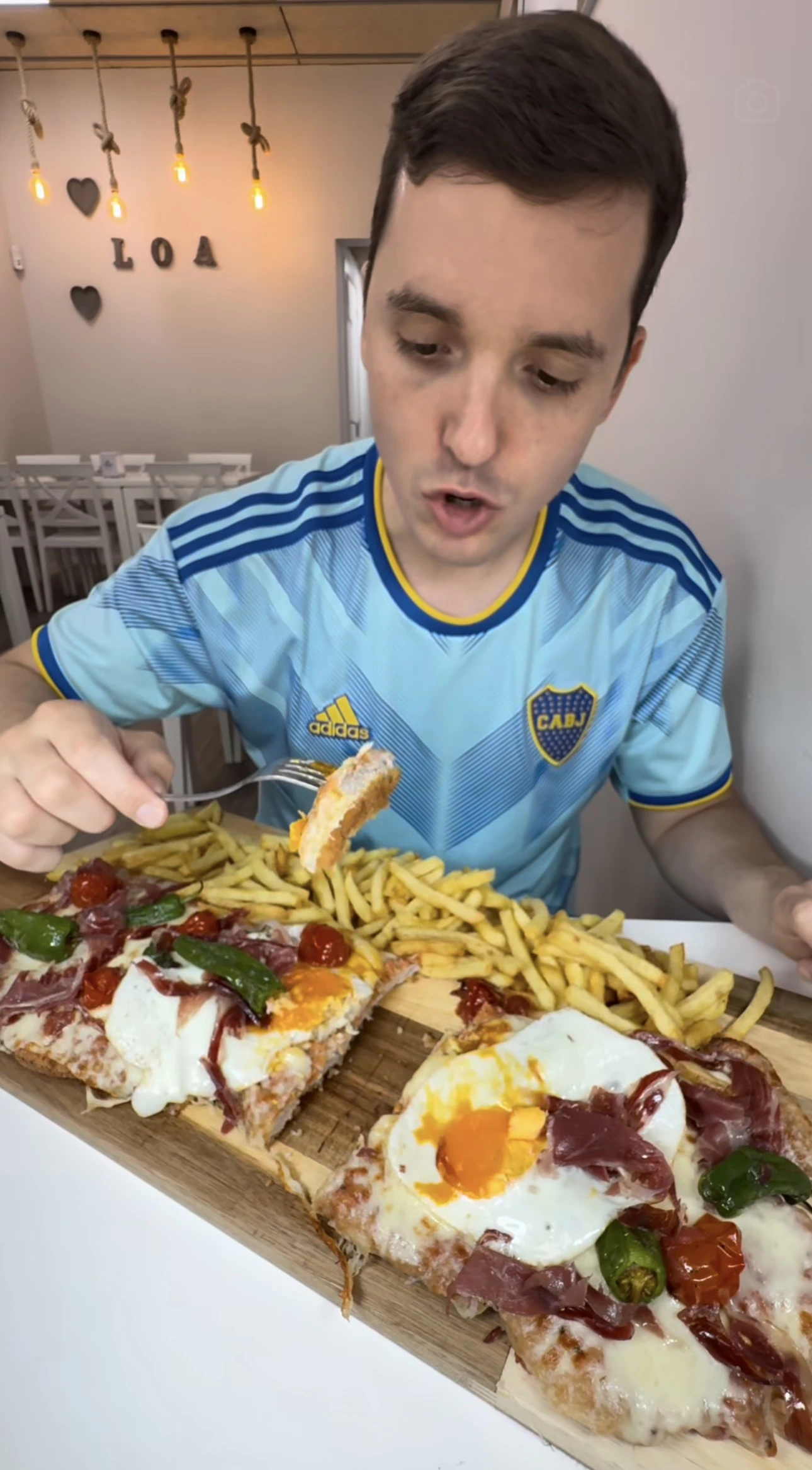 Victor Prous con camiseta de Boca probando un milaneson con huevo, jamón ibérico y pimientos de padrón
